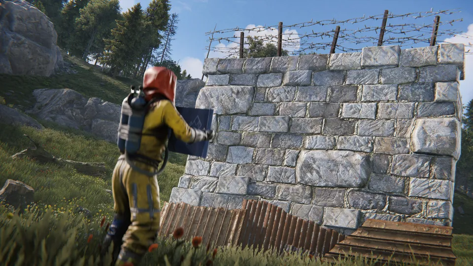 Gracz stawia wysoki kamienny mur przy swojej bazie w Rust