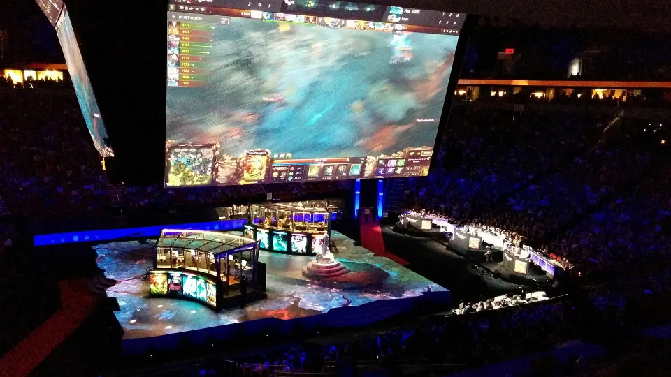 Szene aus dem Finale von The International 2015: die Spieler-Kabinen der beiden Teams und die große Leinwand mit dem Match über der Arena